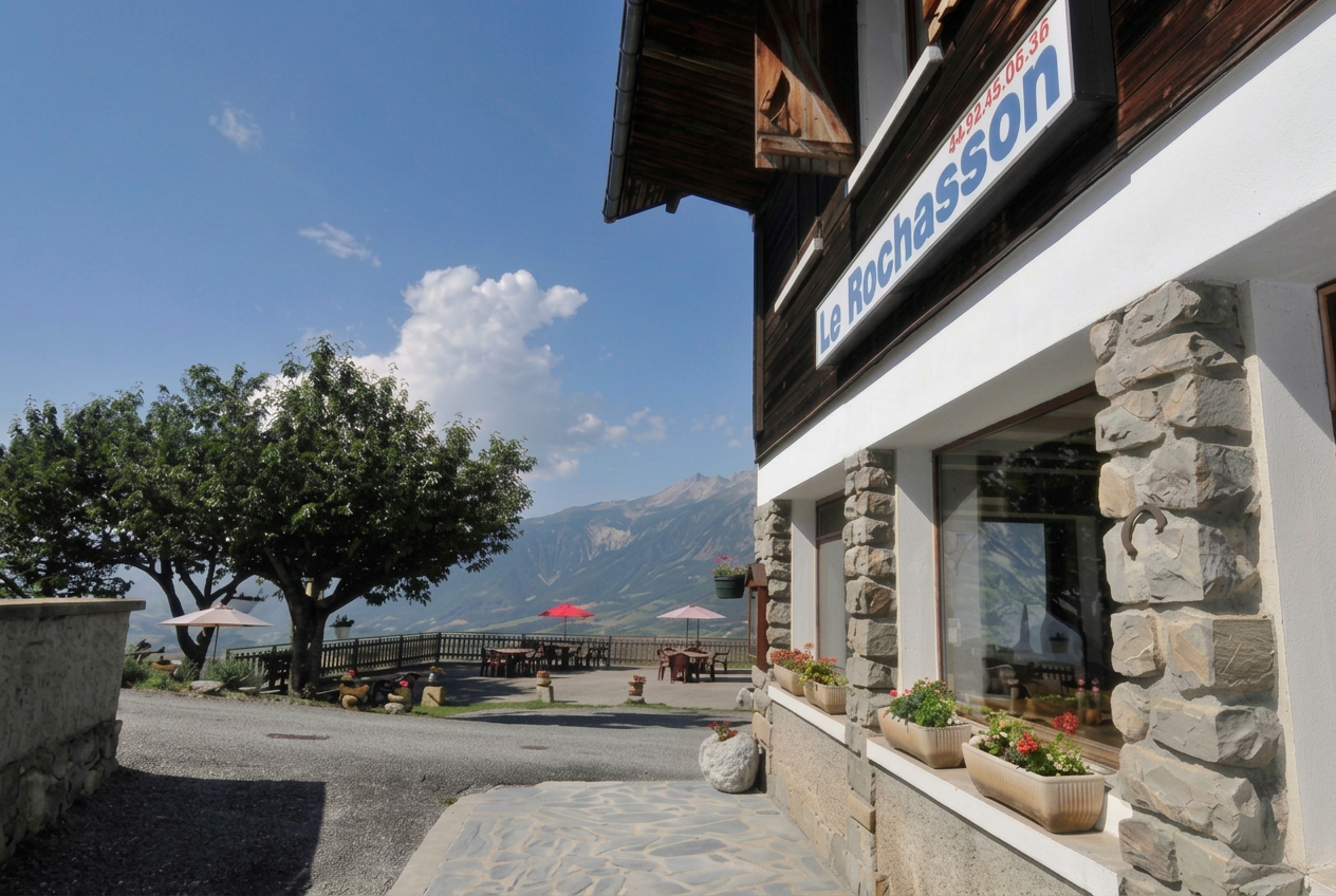 Auberge Le Rochasson en été — façade en bois avec vue sur les montagnes verdoyantes de Risoul